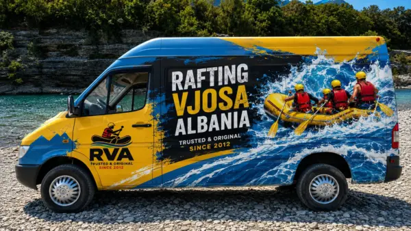 Rafting Vjosa Albania van with a raft painted on the side, parked on the gravel bank of the Vjosa
