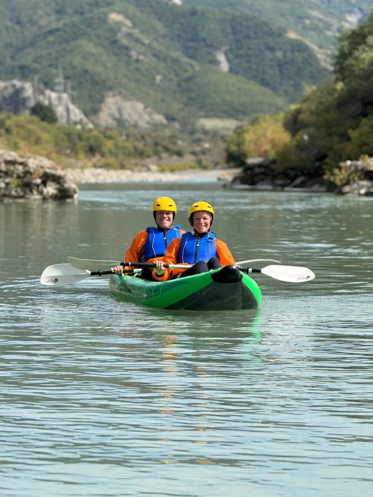 Two-person kayak on the Vjosa River with the Përmet mountains behind