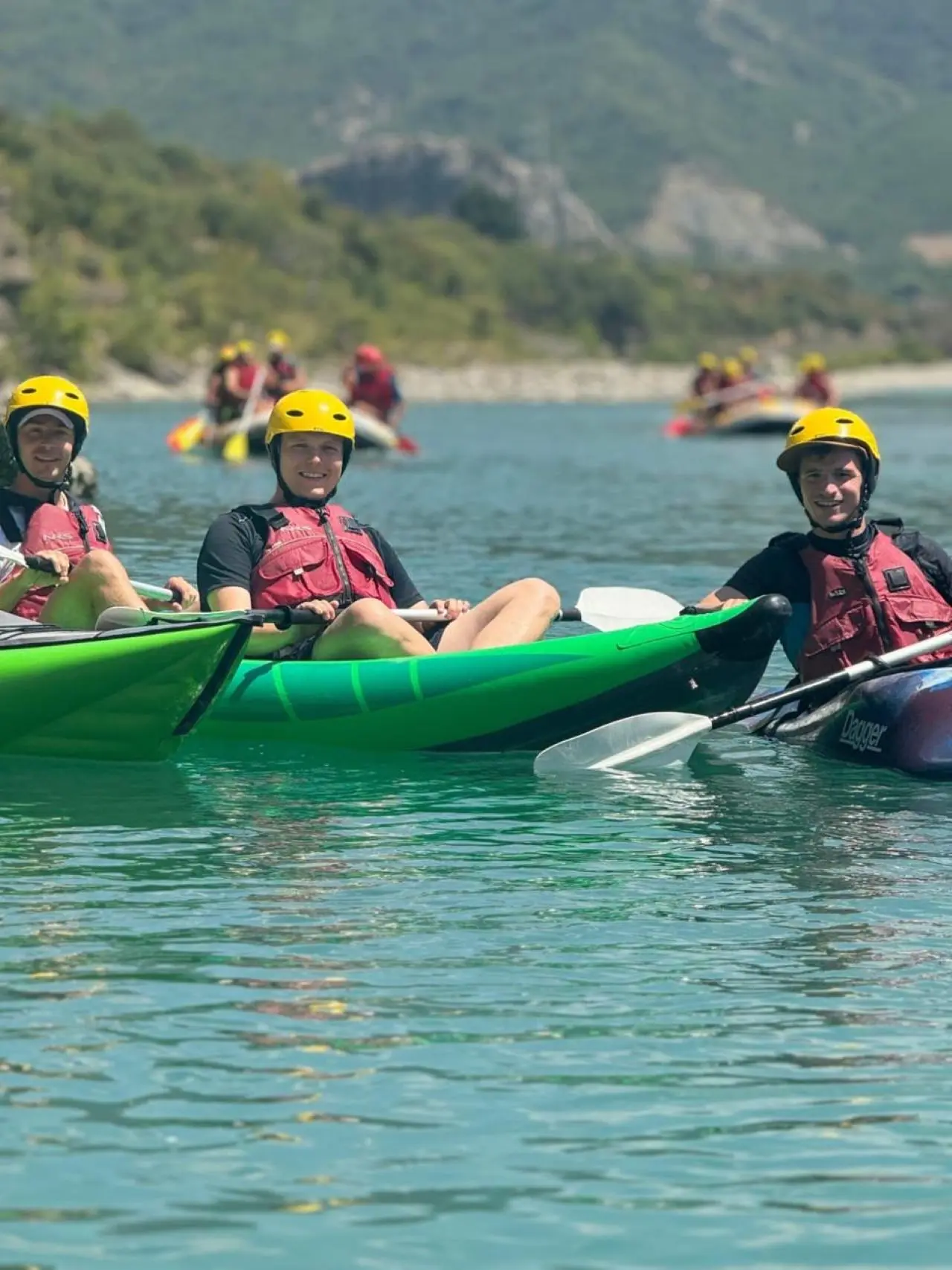 Two tandem kayaks on flat water on the Vjosa River with a raft behind