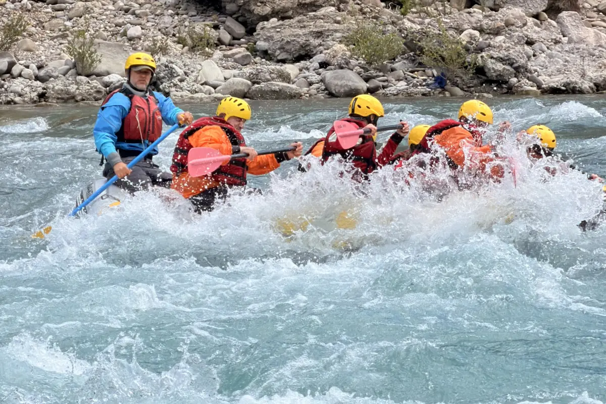 Fotos von der Vjosa 2 Guide steering a raft through a rapid beside a limestone wall on the Vjosa