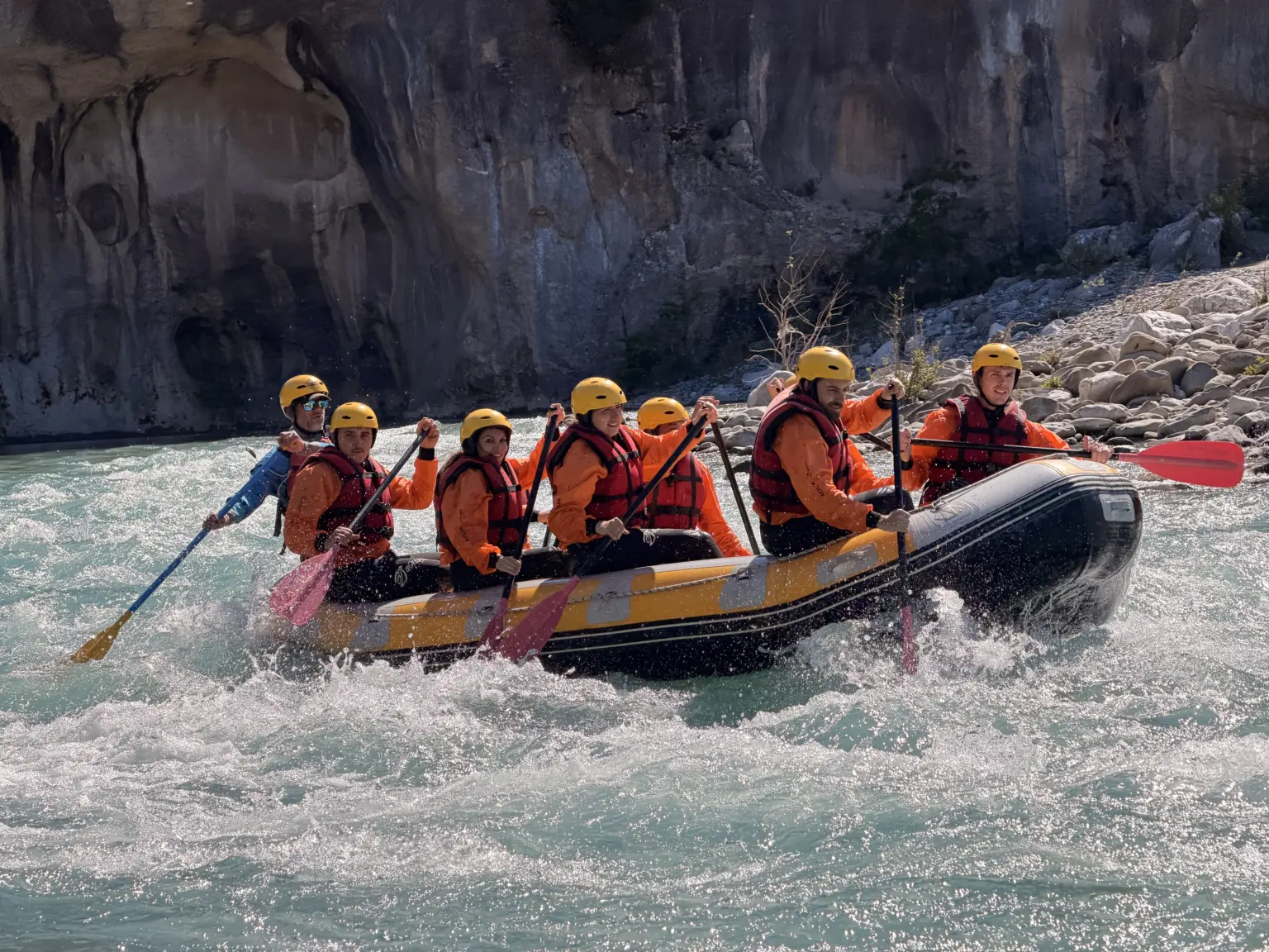 Raft crew paddling into a wave on the Vjosa River in Përmet, Albania