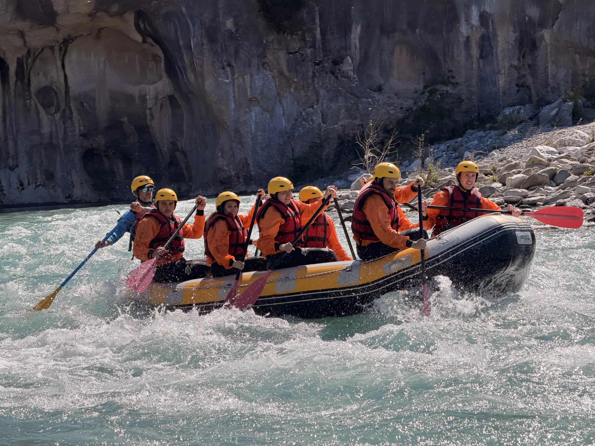 Raft crew paddling into a wave on the Vjosa River in Përmet, Albania